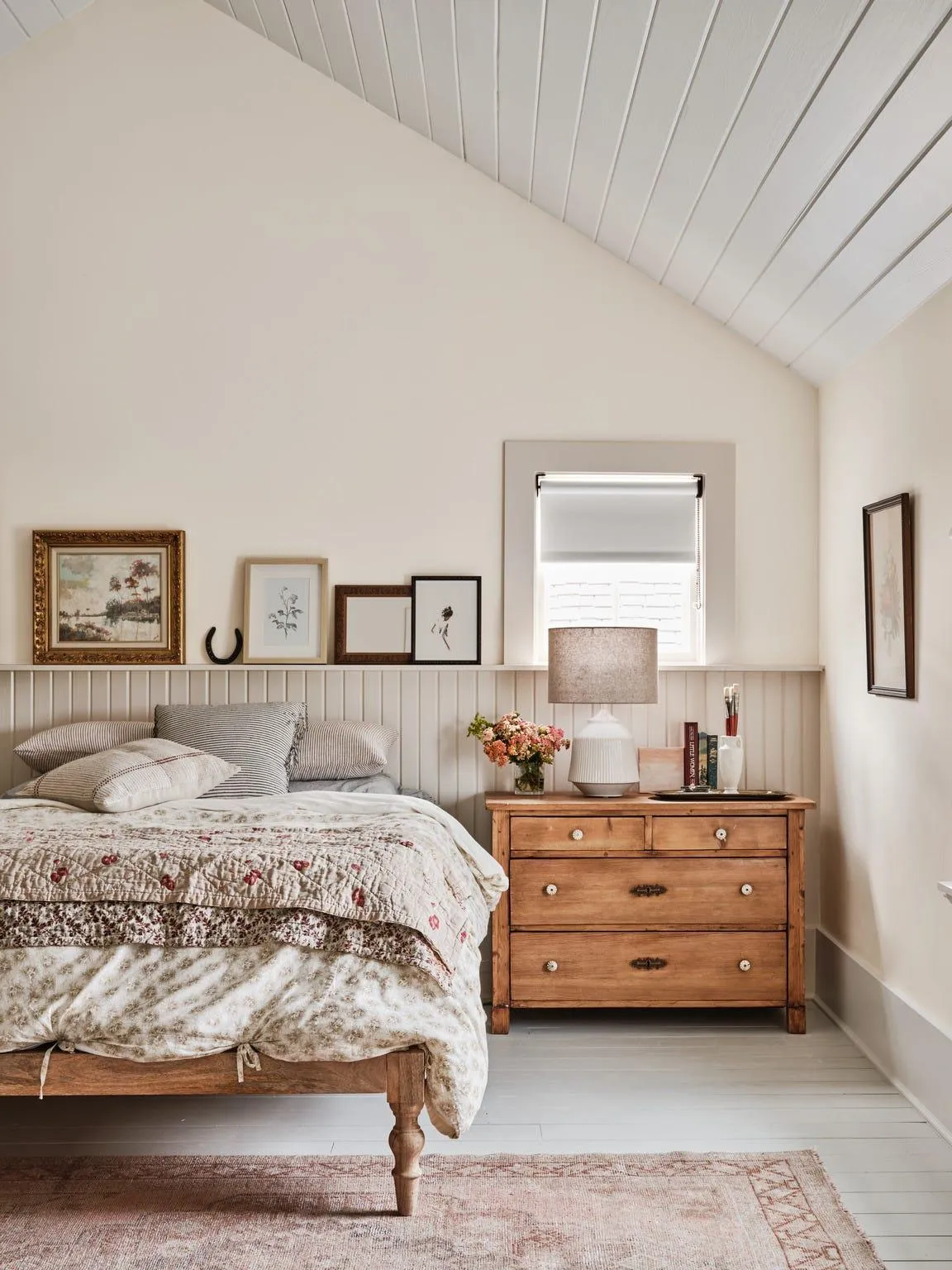 Framed botanical artwork above a wooden dresser in a cottage bedroom