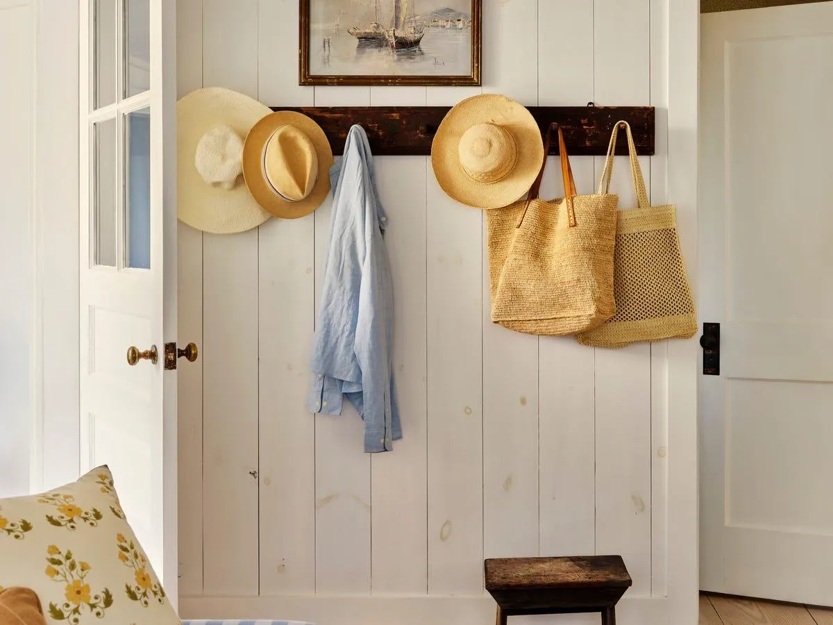 Traditional wall hooks on a wooden board with a woven hat and linen bag